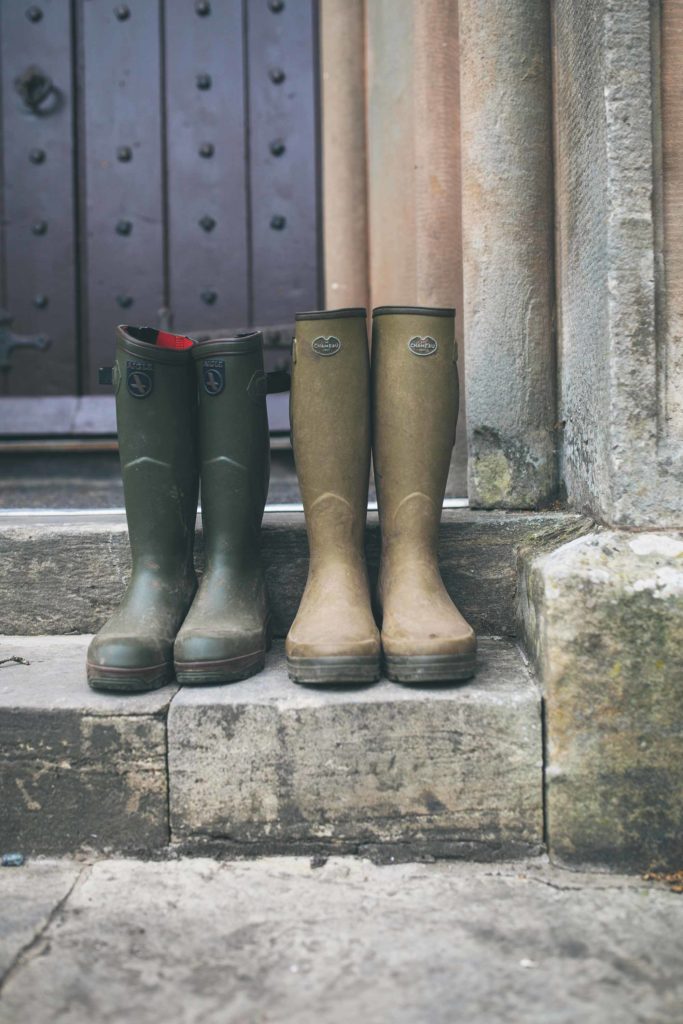 Two pairs of green wellington boots sit on the front step of the castle