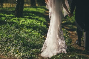 Close up of the bride and groom taking in the woodland walk. The train of the lace wedding dress is the focus