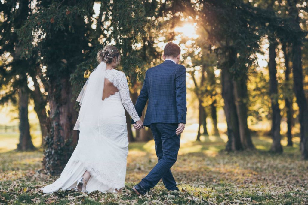 The Bride and Groom, hand in hand taking in the walled garden on an autumn day