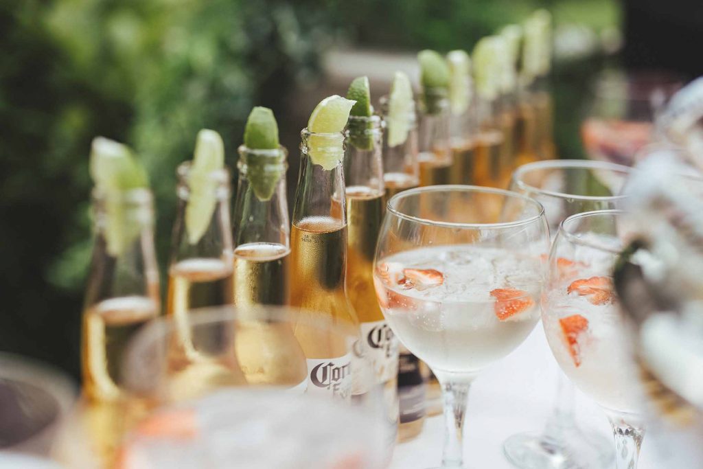 Bottles of corona with lime and balloon glasses of gin and tonic are photographed up close