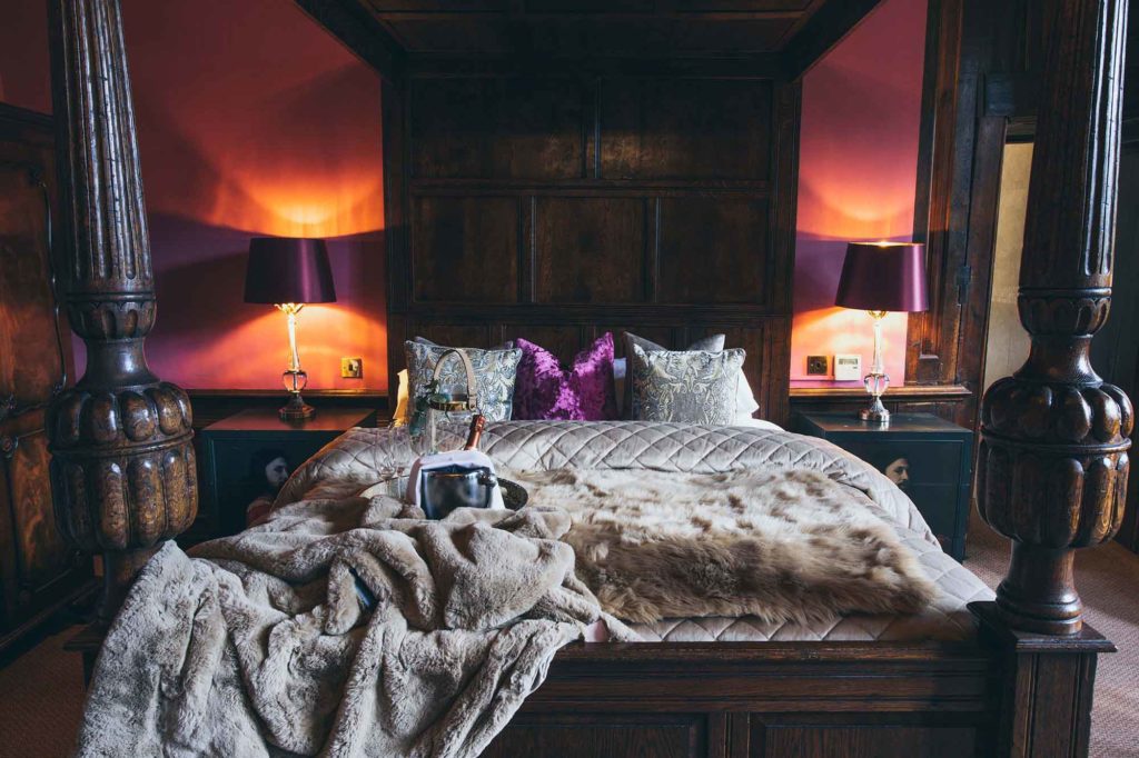 The imposing four poster bed in the honeymoon suite with its plush throws and cushions is captured here