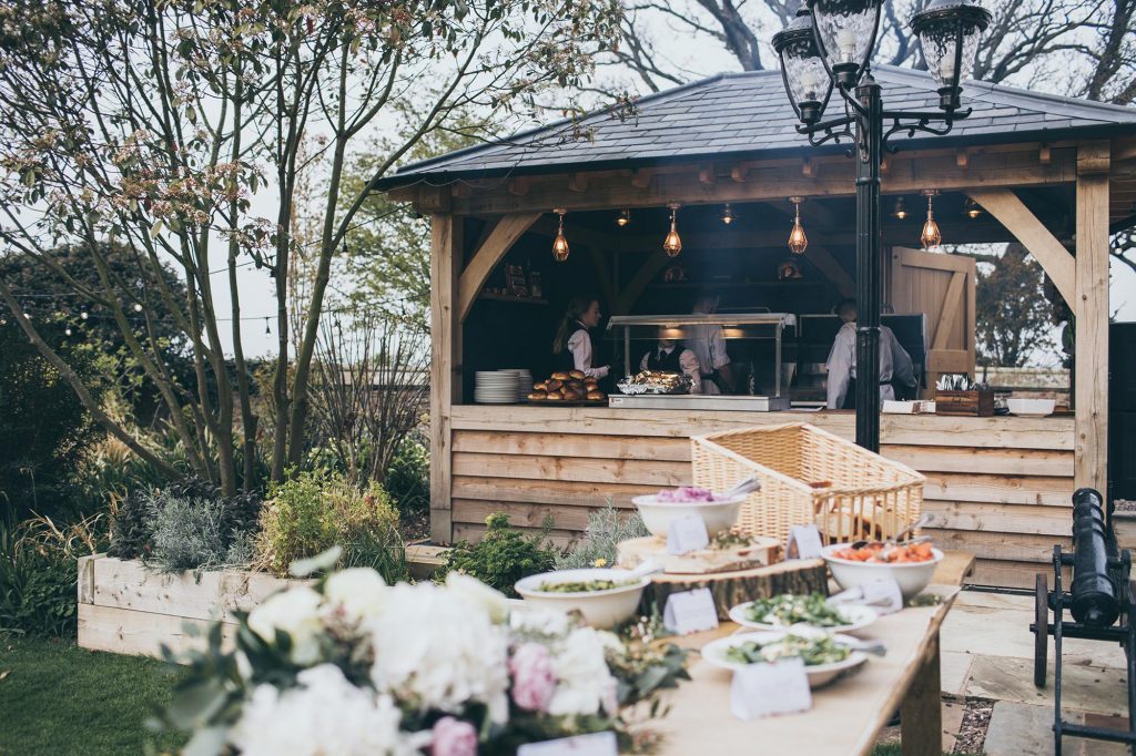 An informal wedding breakfast BBQ being prepared at the castle's terrace grill. Side dishes are presented on a rustic trestle table