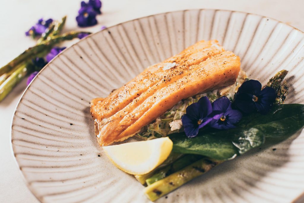 Glorious salmon main course garnished with asparagus and edible violets (food photography)