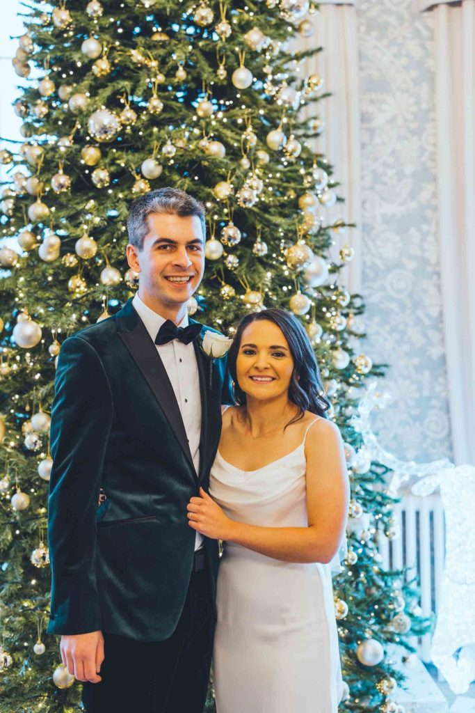 Our Winters Bride and Groom Pose for Pictures in front of the Castle Lounge Christmas Tree