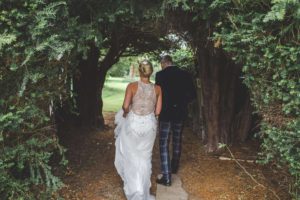 Bride and Groom sneak under the trees into the walled gardens