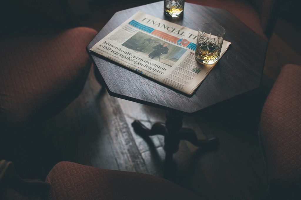 Glasses of whiskey and a copy of the financial times sit atop a table in the castle lounge