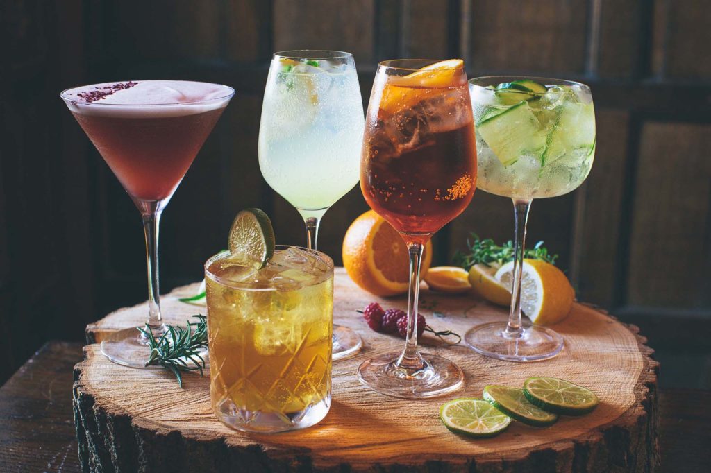 Rowton Castle's collection of signature cocktails are photographed together on a wooden board with accompanying garnishes