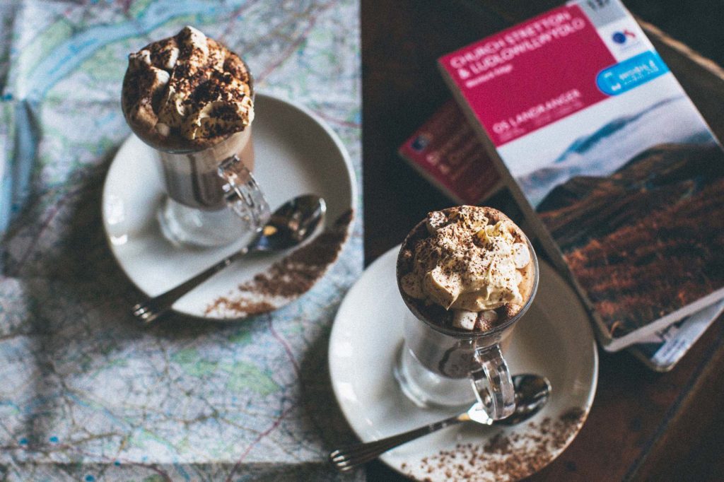 Two luxurious hot chocolates with cream and marshmallows sit atop an ordinance map