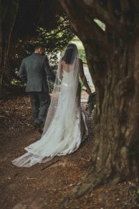 Bride and groom photographed walking through the trees on the winter wedding day at Rowton Castle