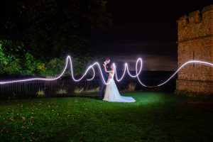 The Bride and Groom embrace by the garden turret with the word love spelled out in sparkler light
