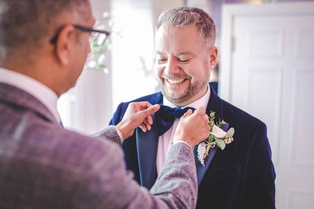 Groom Gurdy helps Groom luke with his blue velvet bow tie ahead of the wedding ceremony taking place