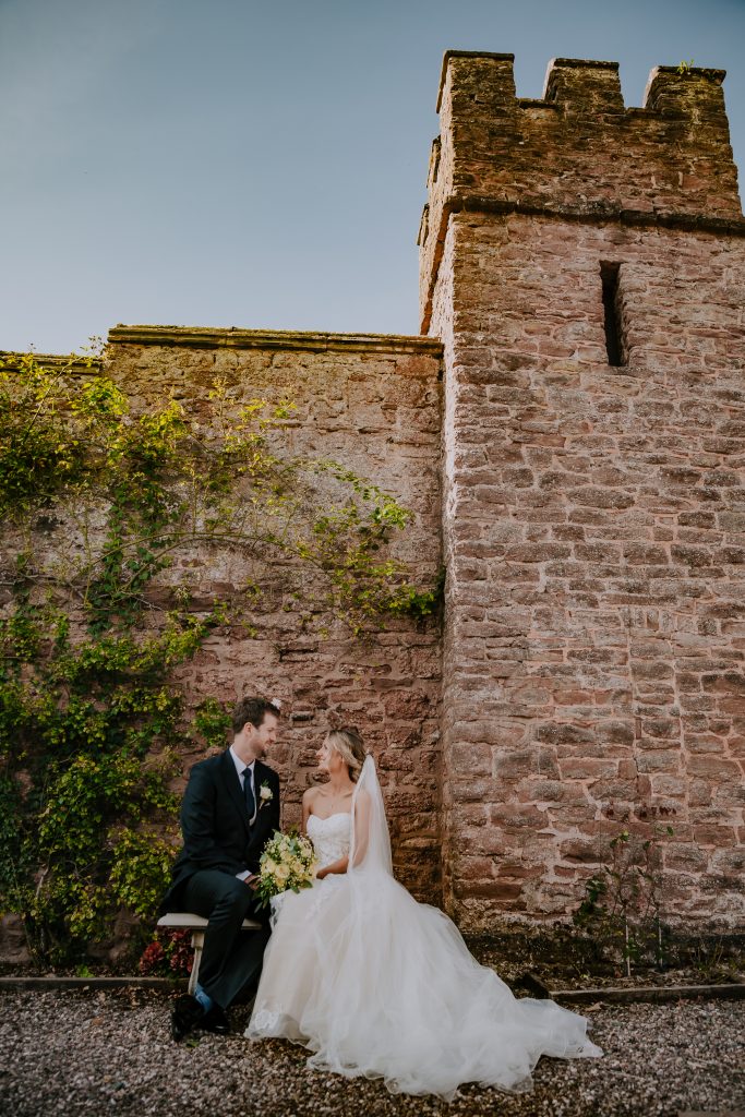 A portrait of the newly married couple in front of the turreted castle walls