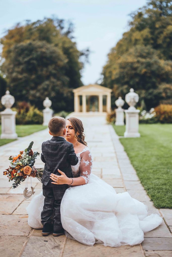 The bride embraces her small son in a photograph taken in the castle gardens on an autumnal day