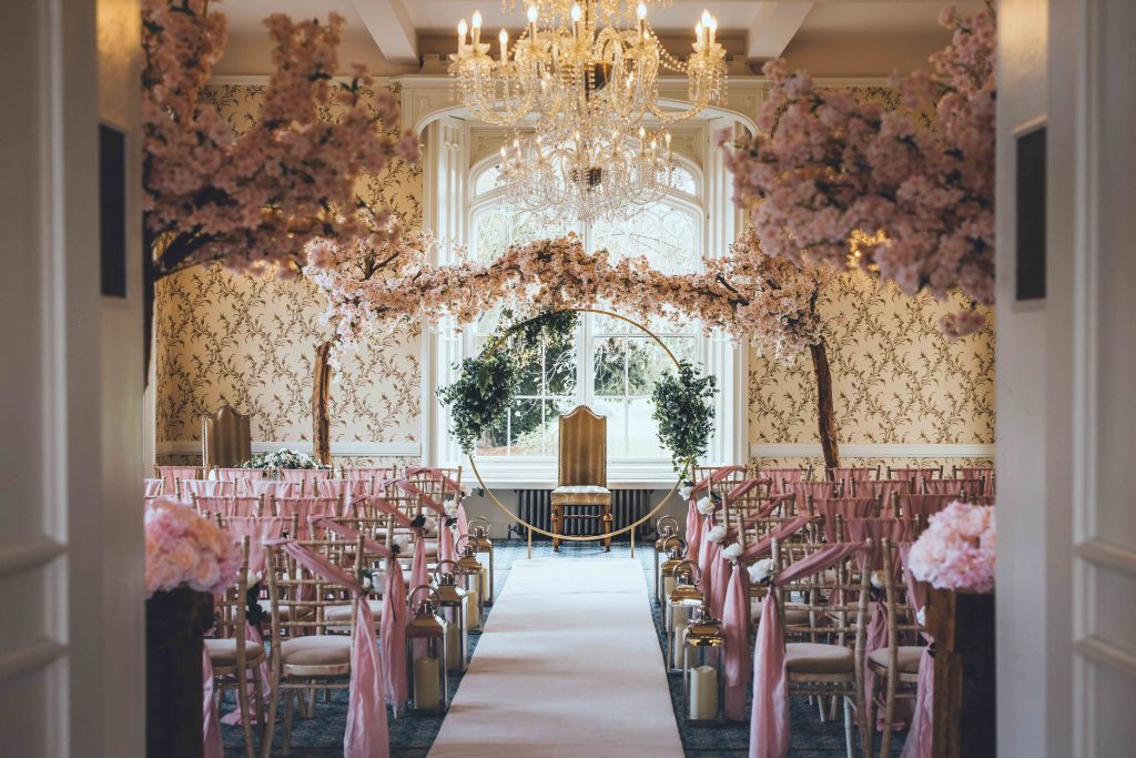 The Cardeston Suite is dressed beautifully in shades of pink. Lanterns line the aisle and blossom trees frame the couple