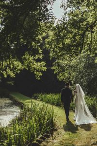 The bride and groom walk beyond the ponds toward the walled gardens at Rowton Castle