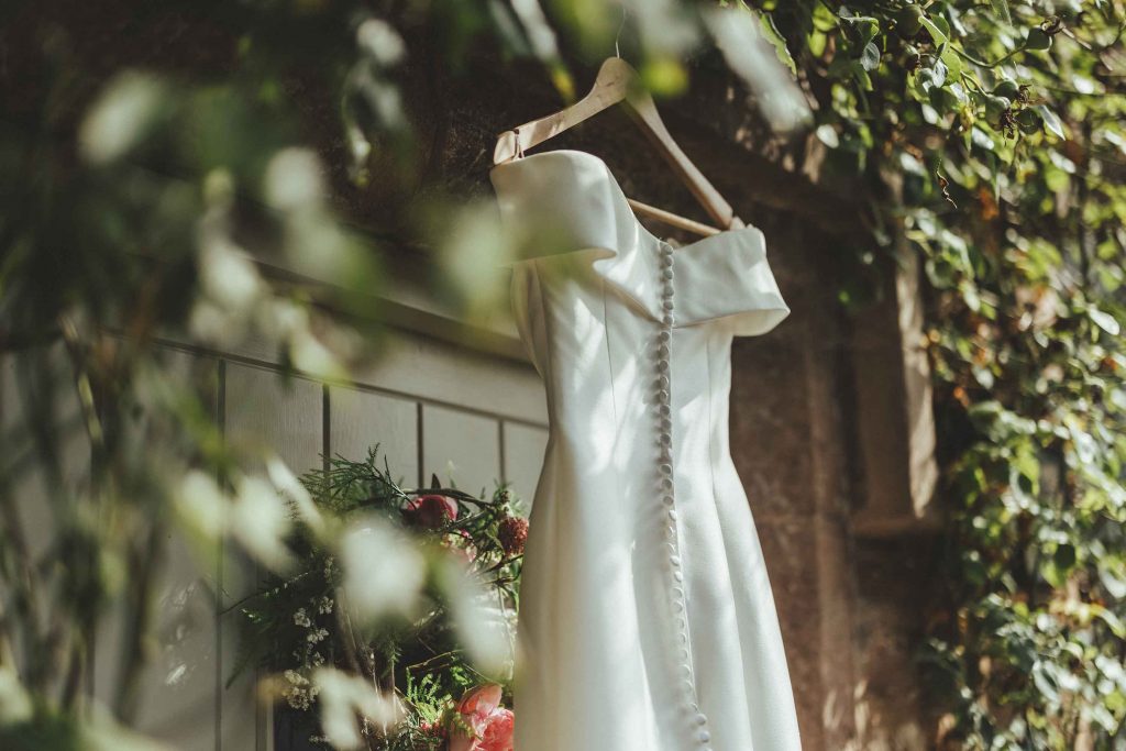 The brides off shoulder wedding dress hangs in front of tower house
