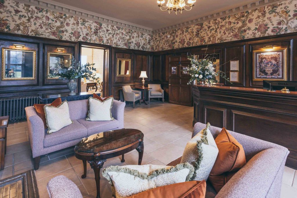The Castle's reception area has been captured with its dark panelled walls, Lewis & Wood wallpaper and green and rust tones