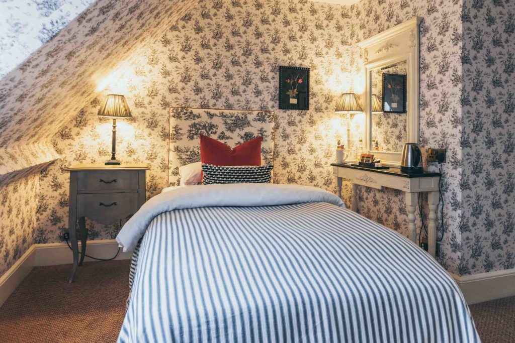 Rowton Castle's Classic Single Bedroom with Black and White Toile Wallpaper and Striped Bed Throw