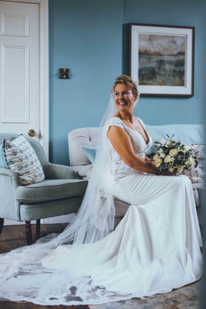 A Bride Dressed in Lace Poses for a Portrait with her Bridal Bouquet