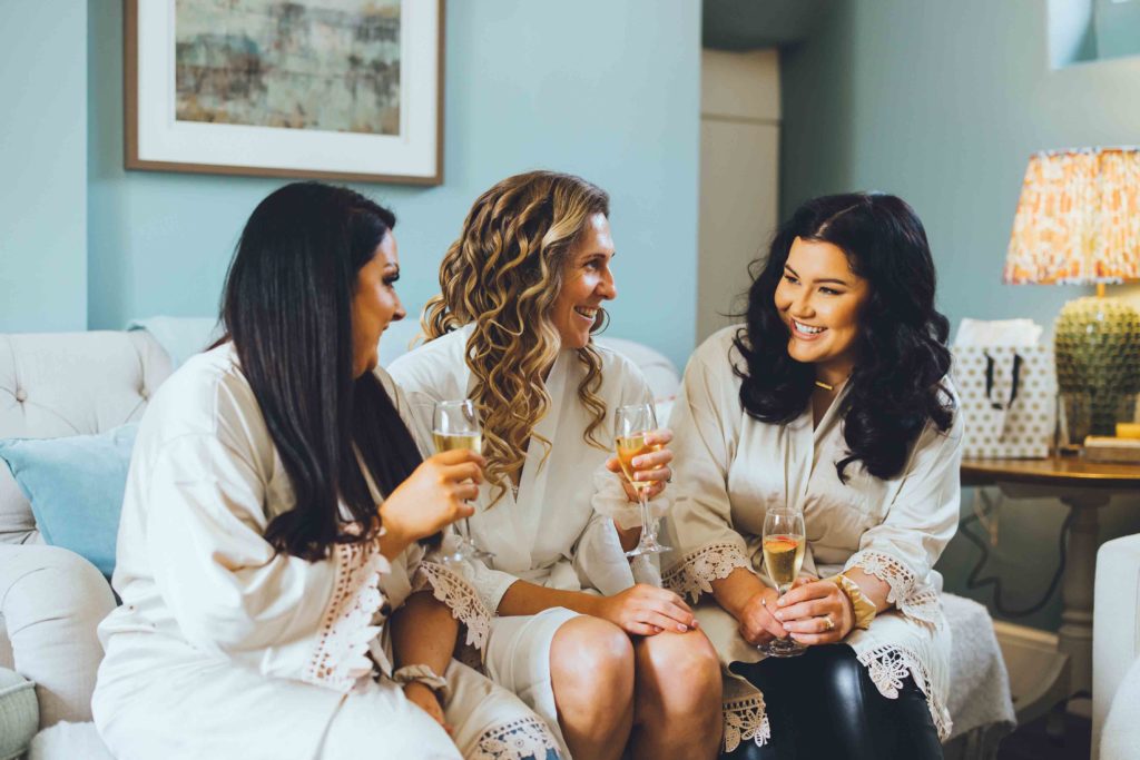 The Bride and her Bridesmaids Sip Champagne seated in the Cosy Orchard Suite Lounge