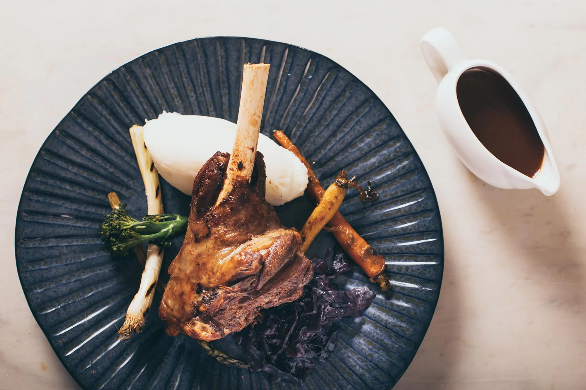Plated lamb shank served with mashed potatoes, seasonal vegetables, and red wine jus at Rowton Castle.