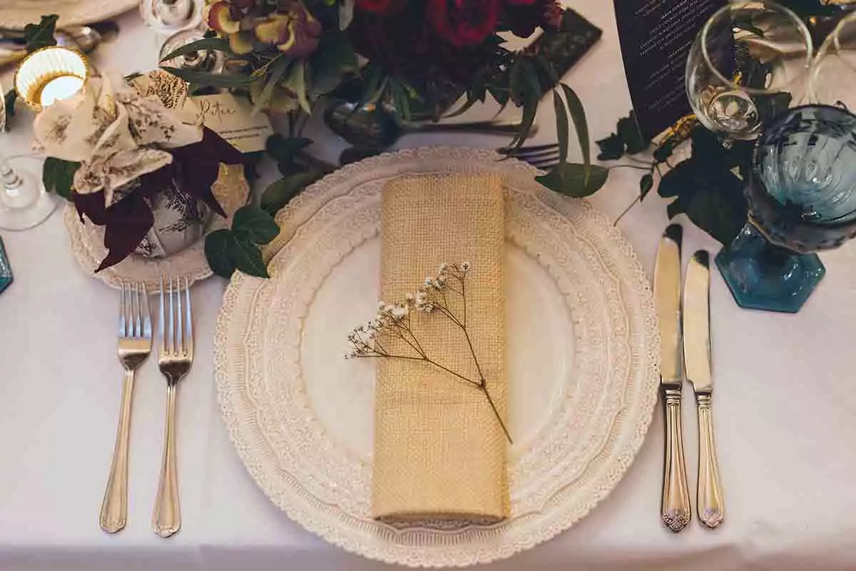 Close-up of a winter wedding place setting with vintage-style crockery, gold cutlery, textured napkin and floral details at Rowton Castle.