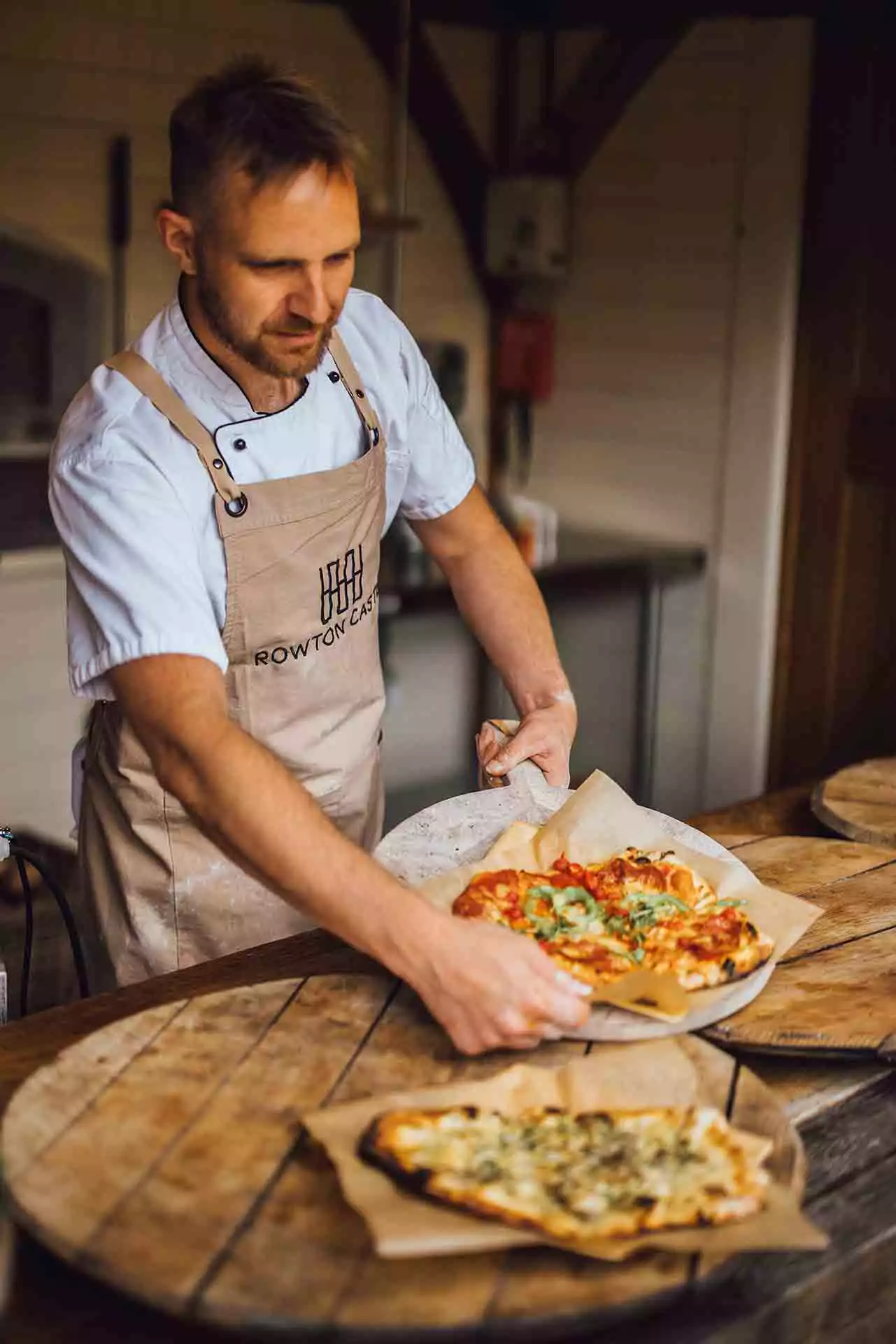 Chef preparing freshly baked pizzas as part of wedding catering at Rowton Castle.