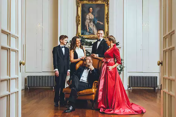 Family dressed in formal evening wear posing in a grand hall at Rowton Castle decorated for a winter wedding