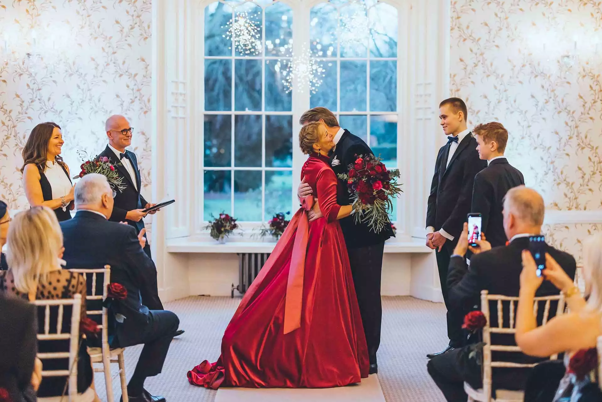 Couple embracing after their ceremony in front of large windows with winter views at Rowton Castle.