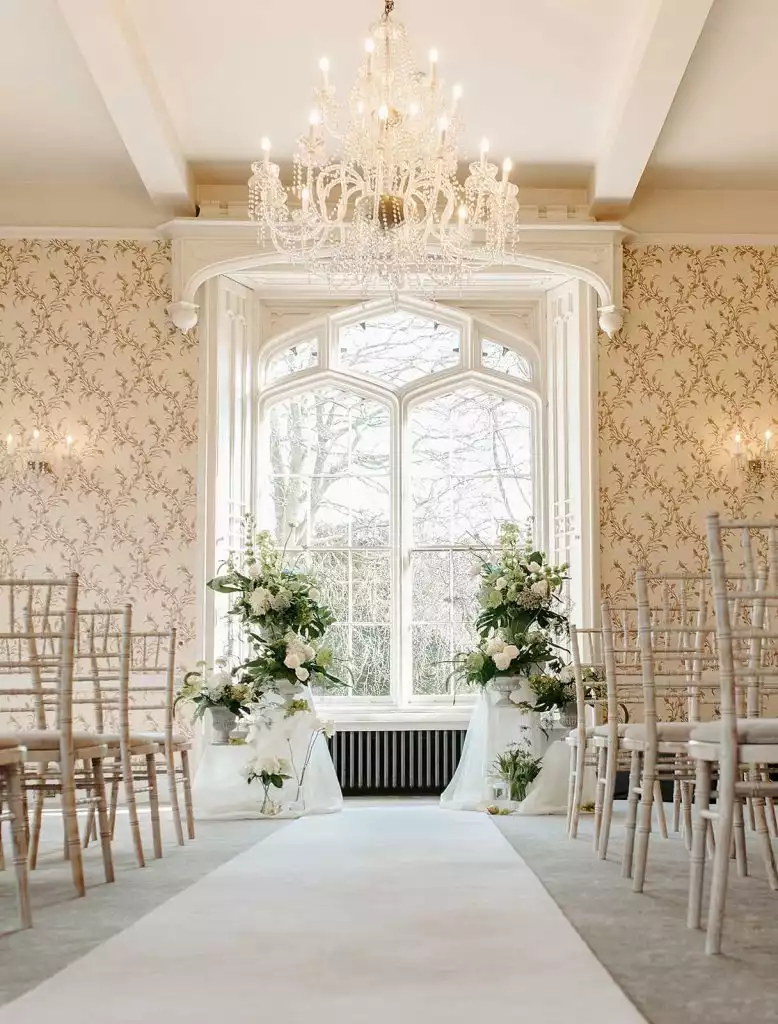 Elegant indoor wedding ceremony setup at Rowton Castle with chandelier, aisle runner and floral arrangements