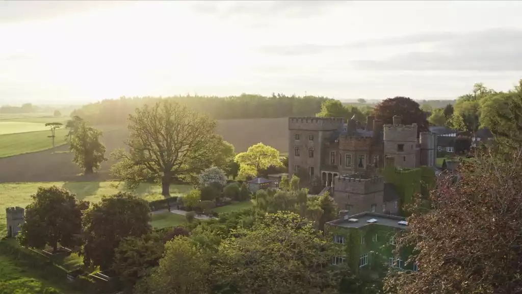 Rowton Castle wedding venue in Shropshire, a historic red-brick castle set within landscaped gardens and rolling countryside at golden hour.